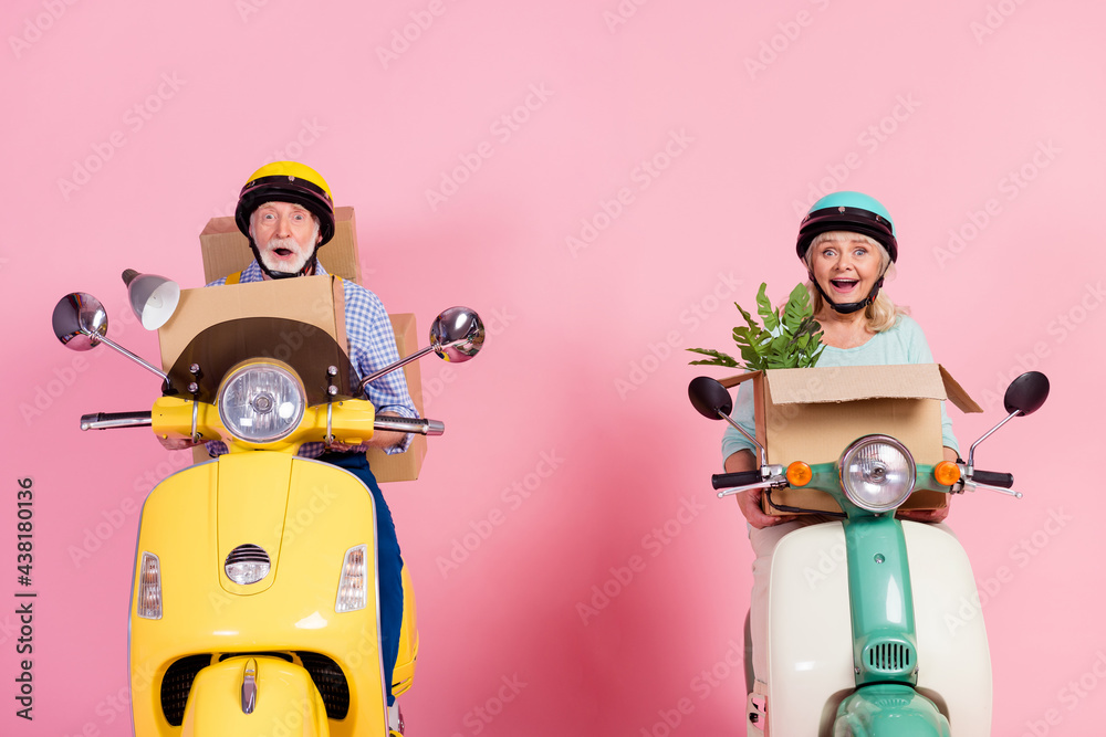 Sticker Photo of happy mature married couple wear casual style in helmet drive moped relocation isolated on pink color background