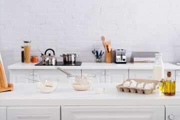 Eggs, milk and flour near digital tablet on kitchen table