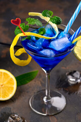 Blue lagoon cocktail with blue curacao liqueur, vodka, lemon juice and soda. Blue cocktail in martini glasses on black background