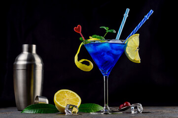 Blue lagoon cocktail with blue curacao liqueur, vodka, lemon juice and soda. Blue cocktail in martini glasses on black background