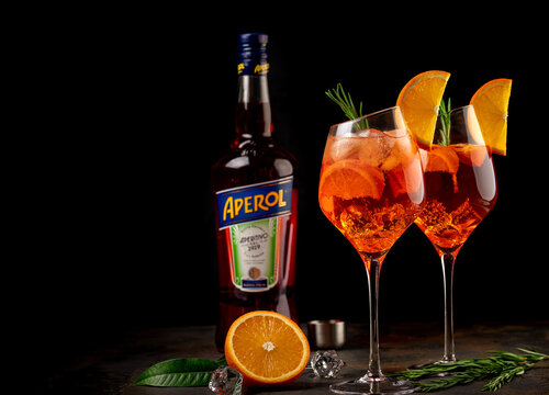 Monchegorsk, Murmansk region Russia. June 1, 2021. Wineglass of ice cold Aperol spritz cocktail served in a wine glass, decorated with slices of orange and rosemary branch with bottle Aperol.