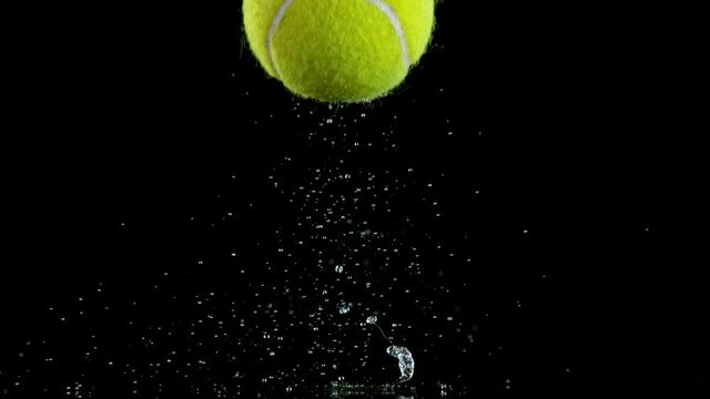 Super slow motion of falling tenis ball on water surface with water splashing during impact, black background, 1000 fps.