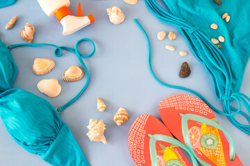 Top view of summer concept,beach accessories with sun oil,summer slippers and seashells on blue surface