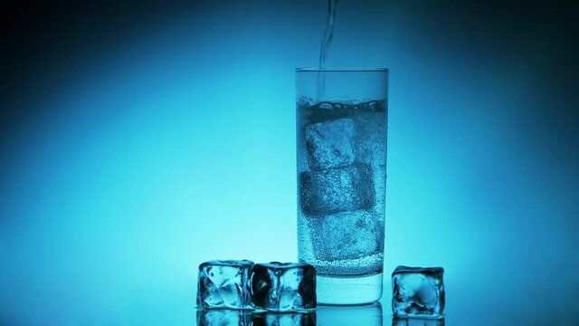 Mineralwasser in ein k&uuml;hles Eisw&uuml;rfel Glas giessen