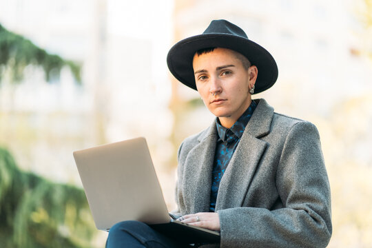 Transsexual person typing on laptop in town