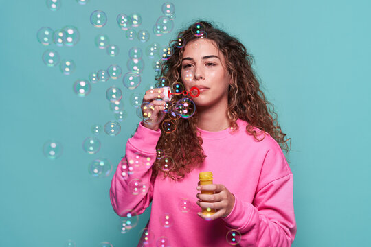Delighted woman blowing bubbles in studio