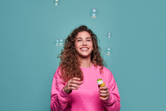 Delighted woman blowing bubbles in studio