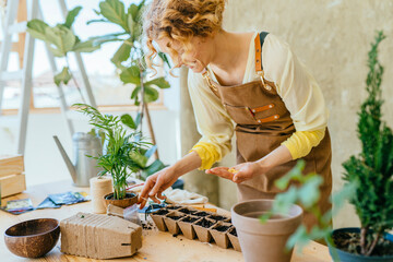 Portrait of happy female gardener working in home garden holds seeds in the palm and sowing seeds...
