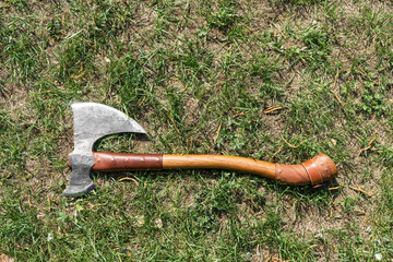 the battle ax is on the ground next to a large stone. forged ax