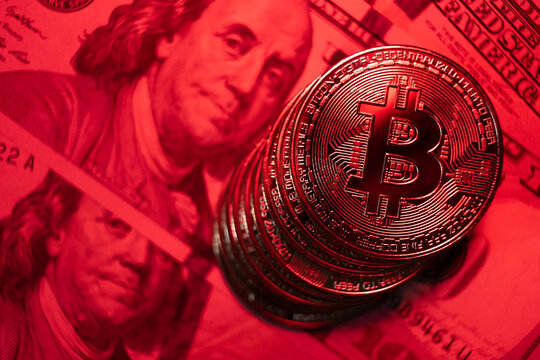 close-up on bitcoin coin with red lighting alluding to falling coin, very short depth of field.