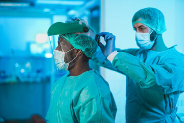 Multiracial doctors preparing and getting dressed to work inside hospital during coronavirus...
