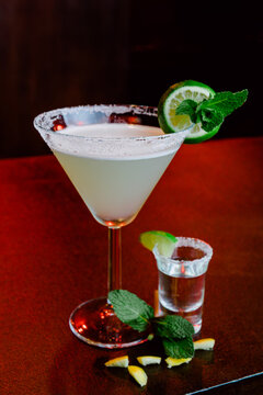 Glass of Margarita cocktail with slice of lime near tequila