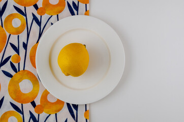 White plate with lemon on a bright summer napkin
