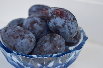 Fresh plum. Autumn harvest. Blue plums in a blue glass dish.close-up front view