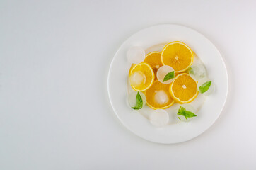 Sliced lemons with ice on a white plate with a white background