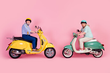 Full size profile side photo of shocked mature married couple riding driving moped scooter isolated on pink color background