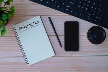 Marketing plan label on notepad with smartphone, coffee, pen and keyboard