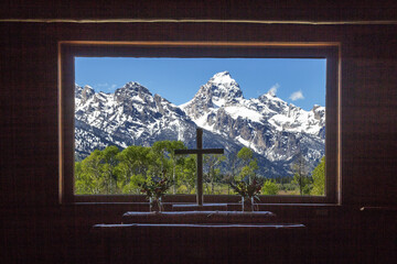 Grand Teton peaks view from the wooden Chapel of Transfiguration window with a Christianity cross in the center
