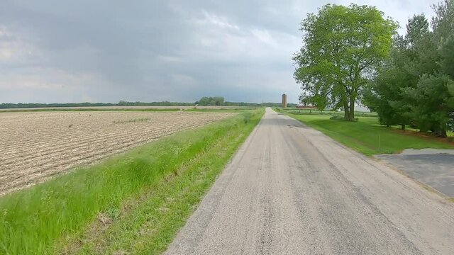 Rear window point of view while on an country road thru northern rural Illinois; driving past empty fields; POV