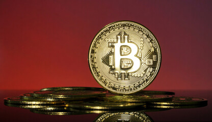 Gold Bitcoins on blur red background. Conceptual image for worldwide cryptocurrency and digital payment system.
