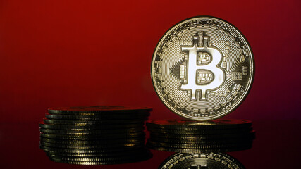 Gold Bitcoins on blur red background. Conceptual image for worldwide cryptocurrency and digital payment system.