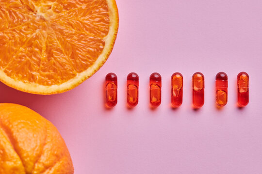 Composition of ripe oranges near row of pills