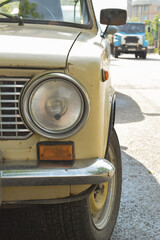 Fototapeta na wymiar round headlight of a vintage old Russian rusty car in beige color close-up.