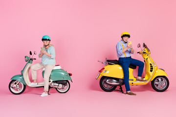 Full size photo of two mature people male female sit moped in helmet casual style addicted to phone isolated on pink color background