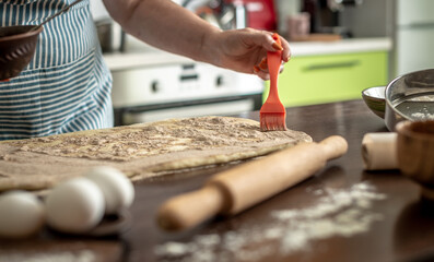 Obraz premium Woman is sprinkling cinnamon on raw dough to make fragrant homemade buns. Concept of the cooking process of baking