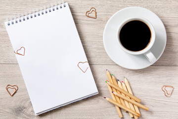 open notebook with blank white sheet and heart shape paper clips on wooden background with white cup with coffee and pencils - Powered by Adobe