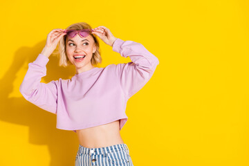 Photo of dreamy young happy blonde lady look empty space wear sunglass isolated on yellow color background