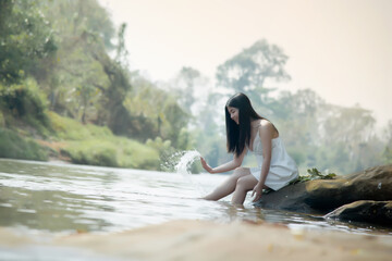 Asian beautifull woman on rock in the river with waterfall