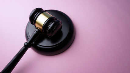 Wooden judge gavel on a pink background. Copy space for text. Legal action concept.
