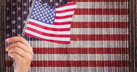 Hand holding a american flag against us flag on wooden background