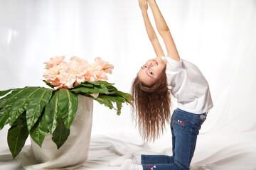 A young gymnast girl with flowers in the studio. Teen athlete posing and doing sports exercises on...