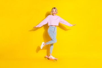 Fototapeta na wymiar Full length photo of young excited girl happy positive smile ride skateboard speed isolated over yellow color background