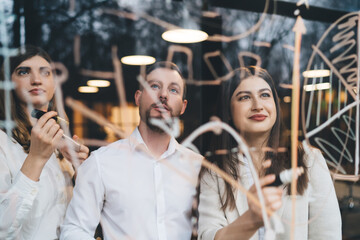 Man and women in formal shirts looking at diagram written on glass window