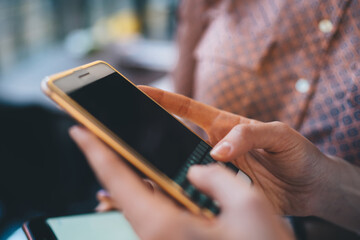 Faceless woman using smartphone with female friend holding digital device