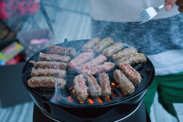 barbecue mit cevapcici auf einem Grill mit Flammen und Rauch.