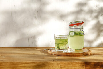 Fresh cold drink with cucumber on wooden desk and wall background. 
