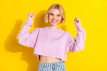 Portrait of attractive cheerful blond girl rejoicing great luck having fun isolated over bright yellow color background