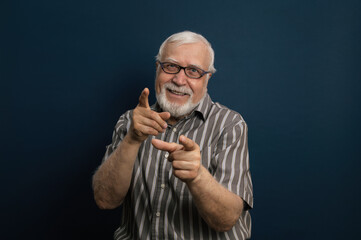 an elderly energetic, charismatic gray-haired man in glasses, points his fingers into the frame, and laughs, emotions in the frame, half-length portrait, blue background, studio