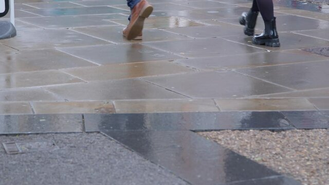 Medium Shot of Pedestrians Walking On a Wet Pavement 