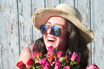 Happy laughing woman with roses in sunglasses
