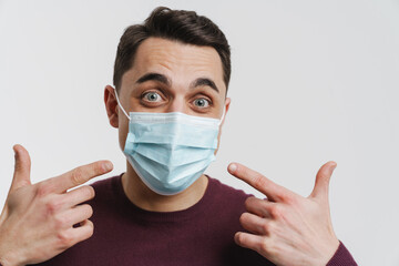 Young brunette surprised man pointing fingers at his face mask