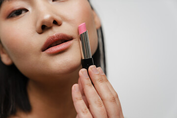 Young asian brunette woman posing and showing lipstick