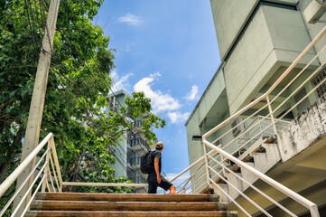 Bottom up view point of young man backpacker walking in public residential area and looking to the sky , inspiration , motivation , freedom , recreation and residential concept