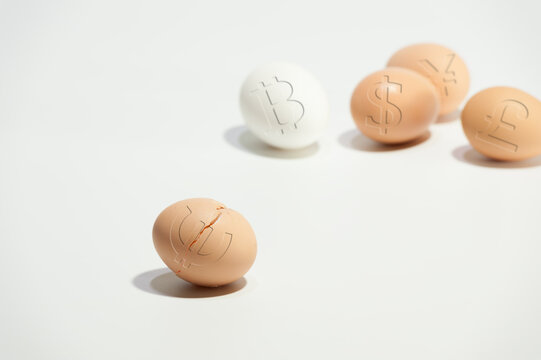 Broken egg with euro symbol on the background of other eggs with world currency symbols