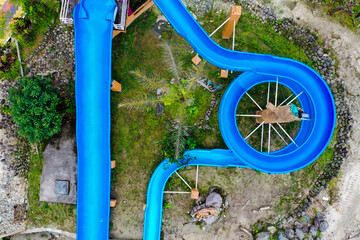 Aerial top view of two waterslides of which one goes straight and the second waterslide goes in circles