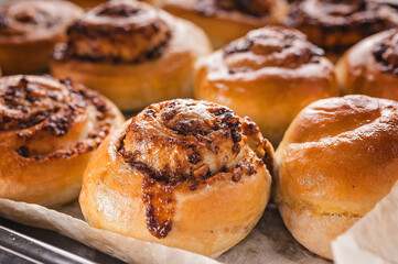 Close-up sweet Scadinavian aromatic cinnamon rolls. Traditional homemade pastry made from butter dough. Delicious buns on baking paper. Winter christmas Scandinavian pastries.